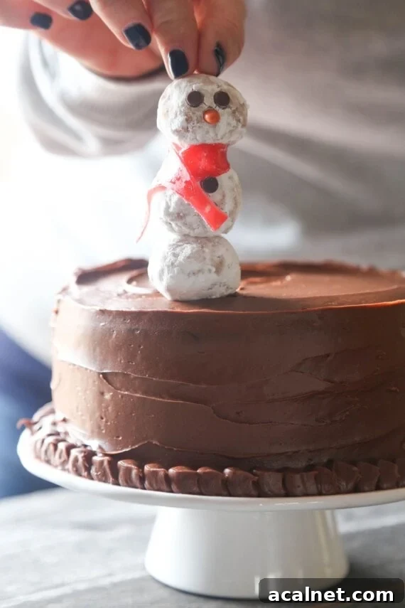 Make sure the bottom is flush with the cake. A snowman cake pop being pressed into the top of a frosted chocolate cake.