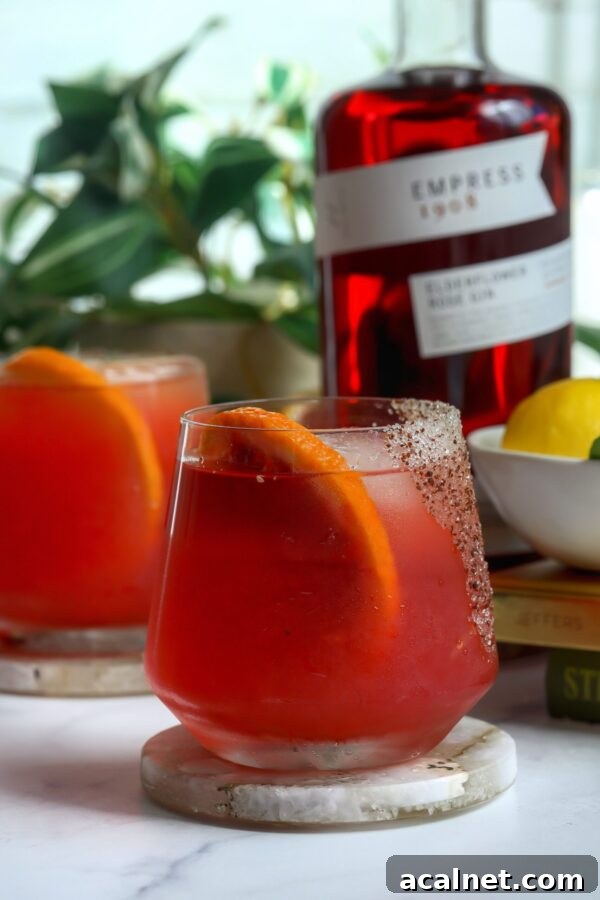 Prickly pear cocktail made with empress gin, with a spicy sugar Rin and a blood orange for garnish.
