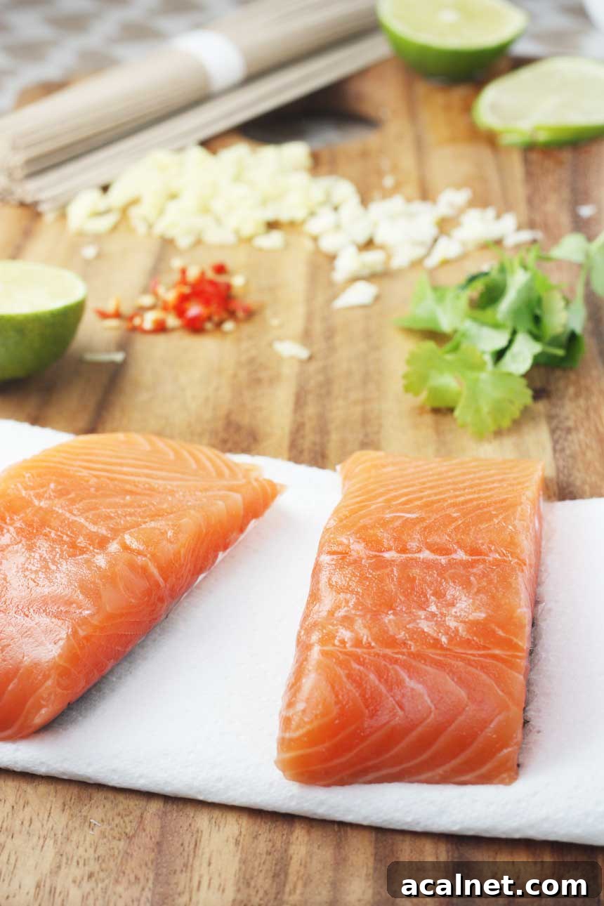 Fresh salmon on a wooden board with ingredients to make teriyaki salmon in the background.