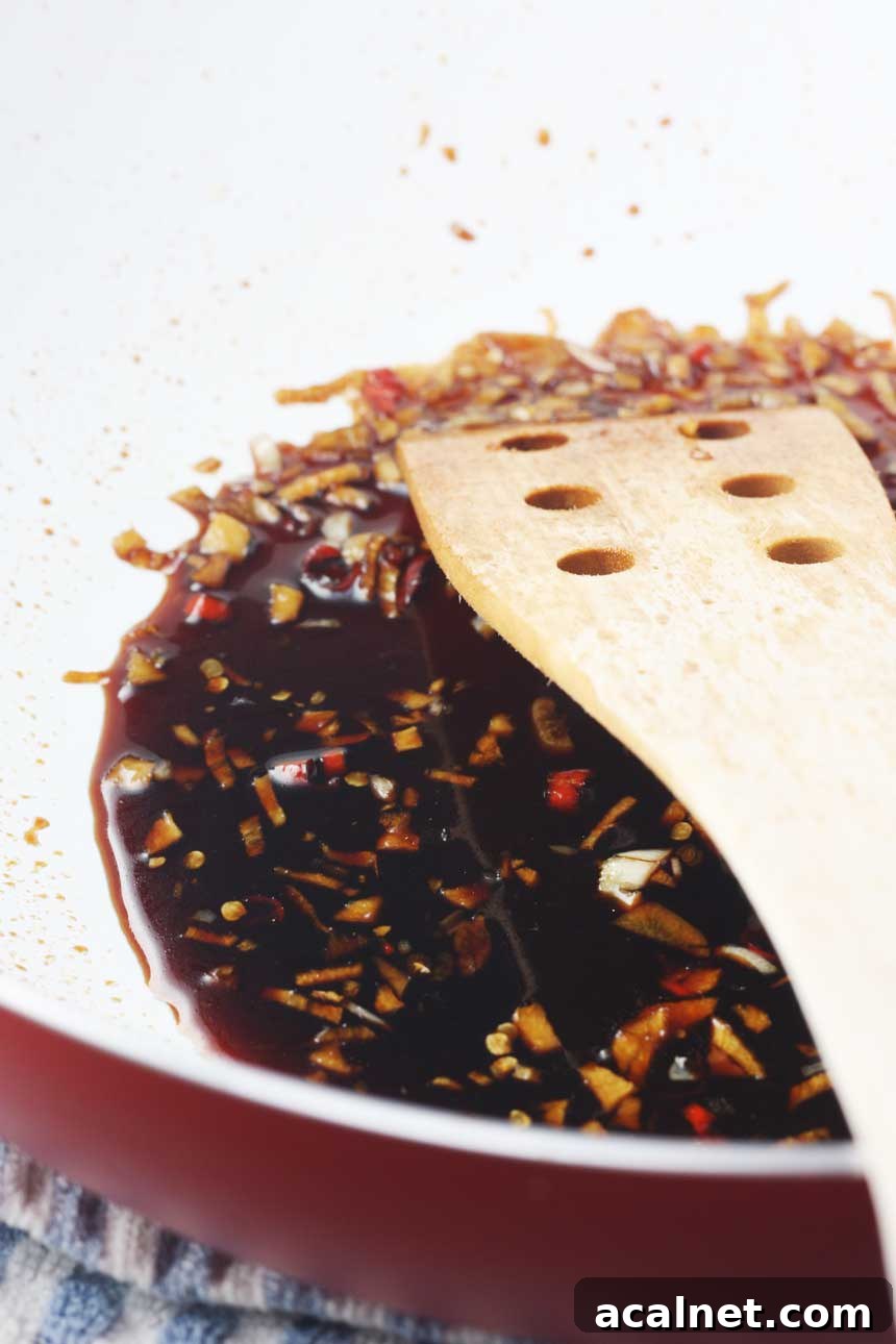 A pan of sauce for teriyaki salmon with a wooden spoon in it.