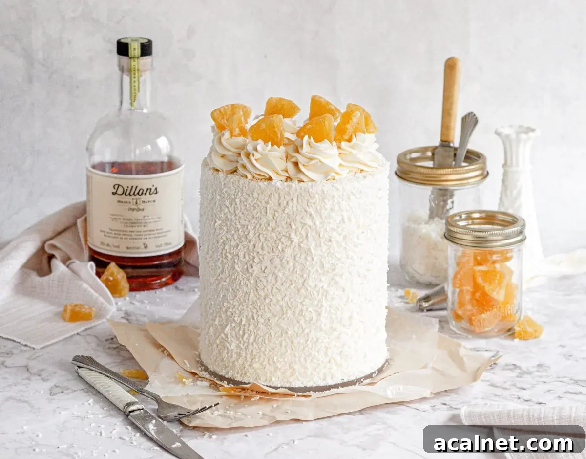 A pina colada cake covered in shredded coconut and topped with white frosting swirls and dried candied pineapples.