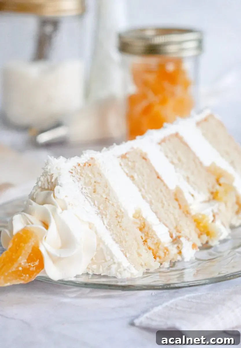 A slice of pina colada cake laying on a plate with white frosting between each cake layer and pineapple filling.