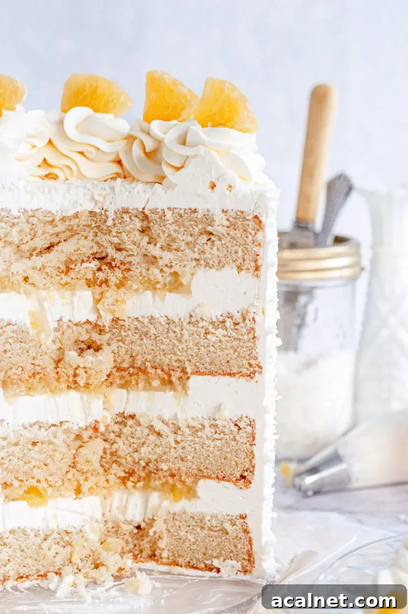 The inside shot of a pina colada layer cake with white frosting between each cake layer and pineapple filling.