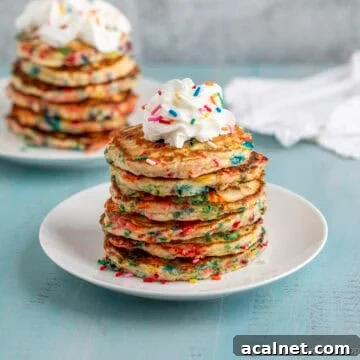 A stack of confetti pancakes topped with a dollop of whipped cream.