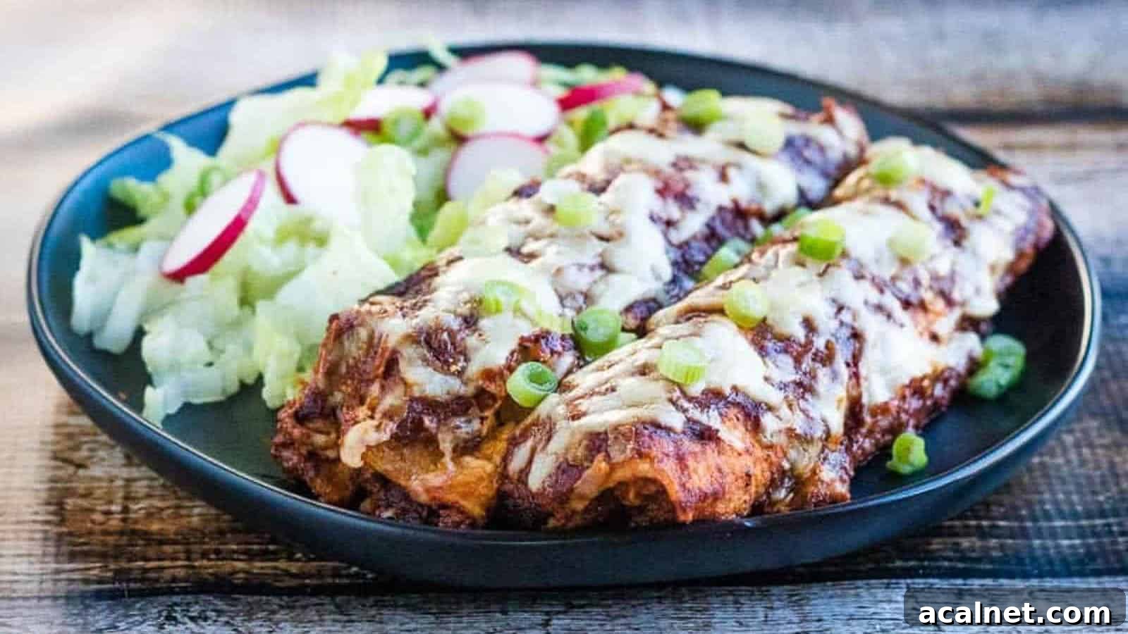 29 Chicken Dinners That Keep Coming Back to Our Weekly Menu 11 Low angle shot of chicken enchiladas on a plate with salad.