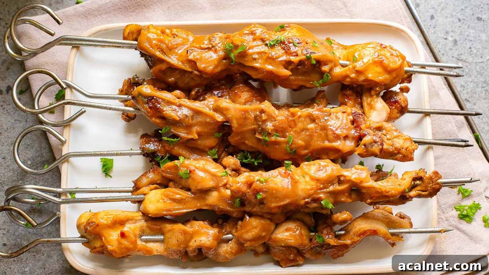 29 Chicken Dinners That Keep Coming Back to Our Weekly Menu 22 Grilled chicken skewers with sauce and garnished with chopped herbs, served on a rectangular white plate.