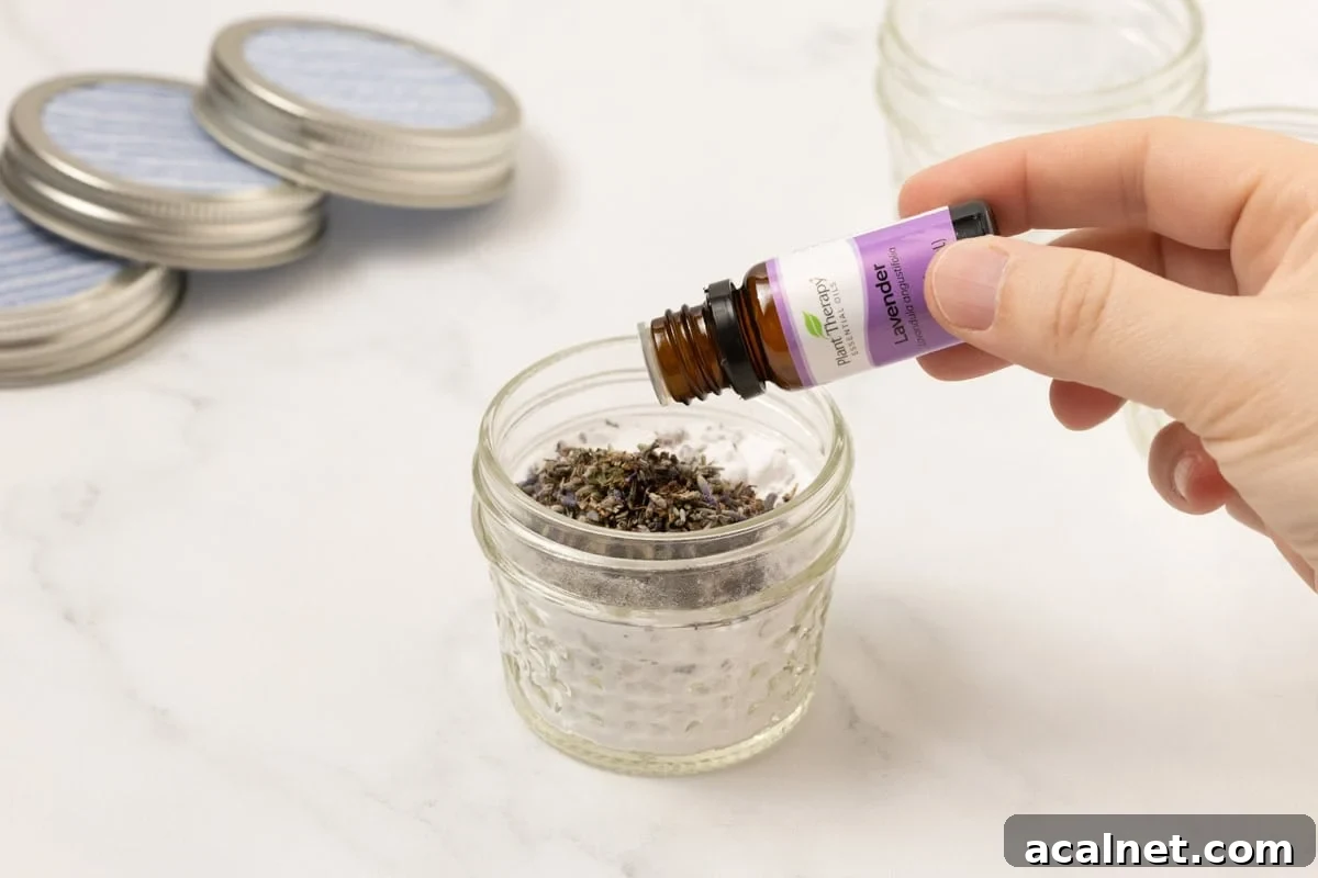 lavender essential oil being added to baking soda and lavender buds in a mason jar