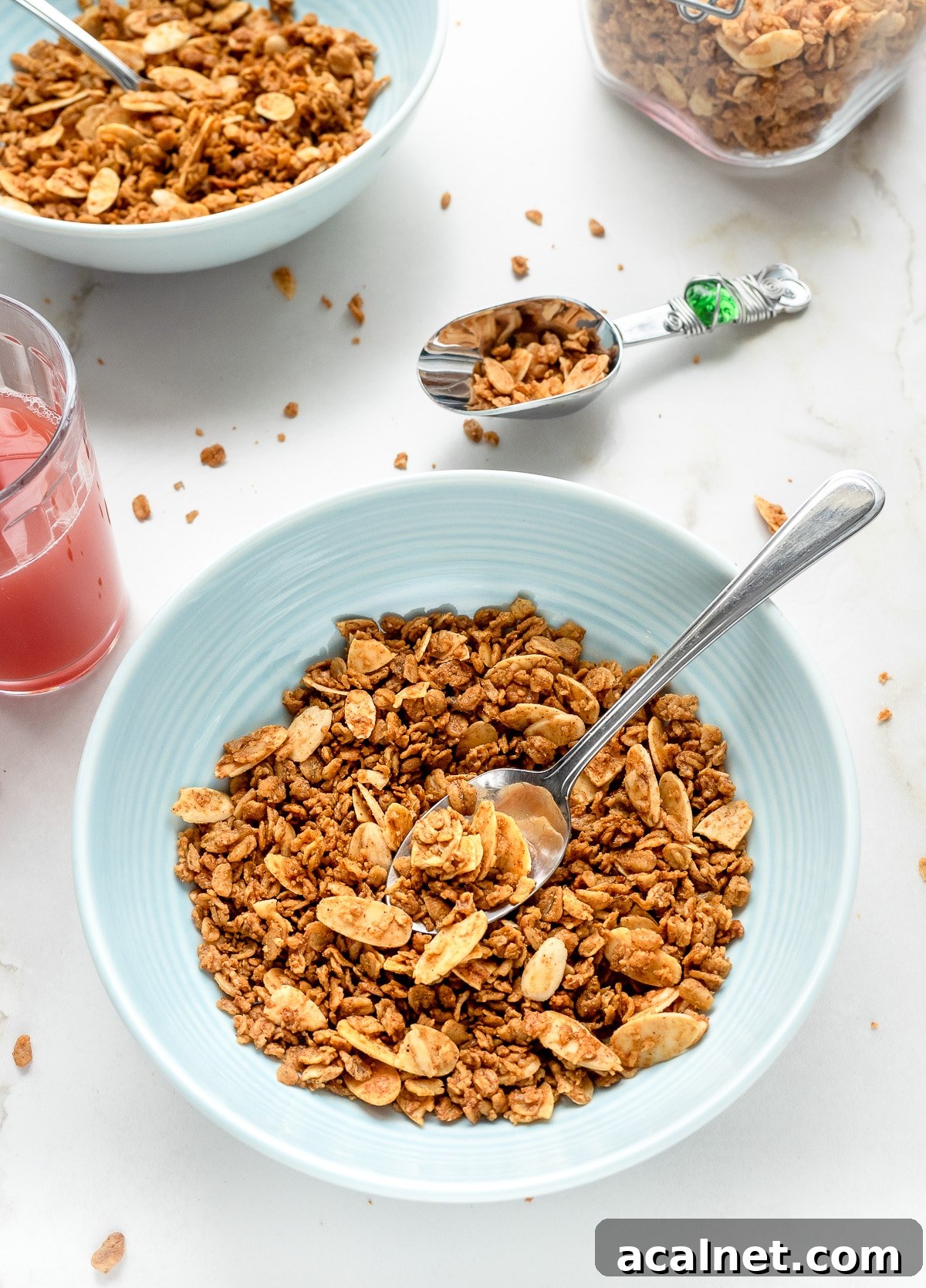 Homemade vanilla almond granola in a bowl with glass of juice next to it.