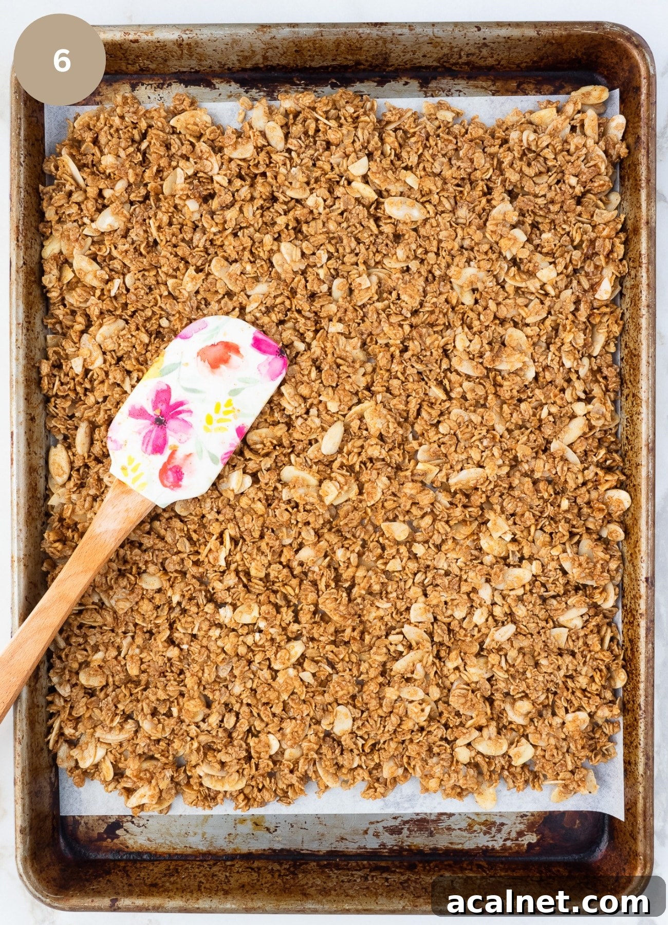 Baking sheet with almond granola spread out on it.