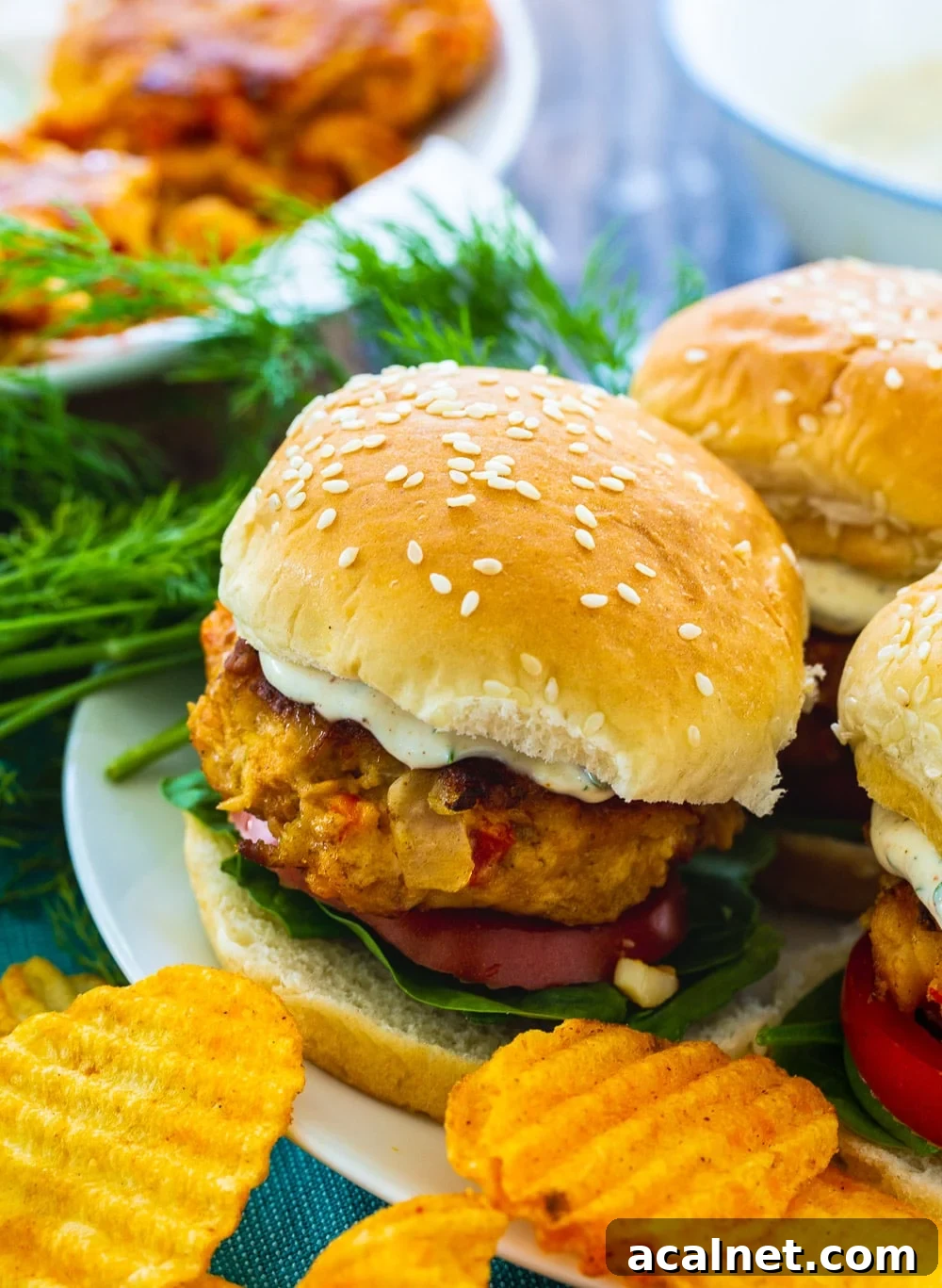 Three Crawfish Burgers on a plate with chips.