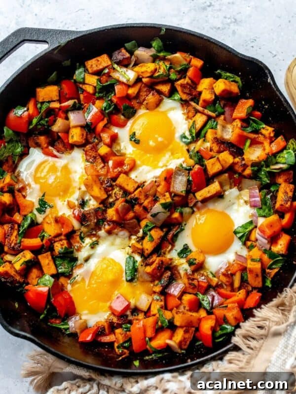 Black skillet with Sweet potato hash in it and eggs on top.
