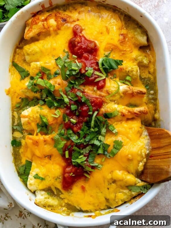 White casserole dish with Breakfast Enchiladas in it and wooden spatula.