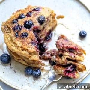 healthy whole wheat pancakes with berries and a silver fork.