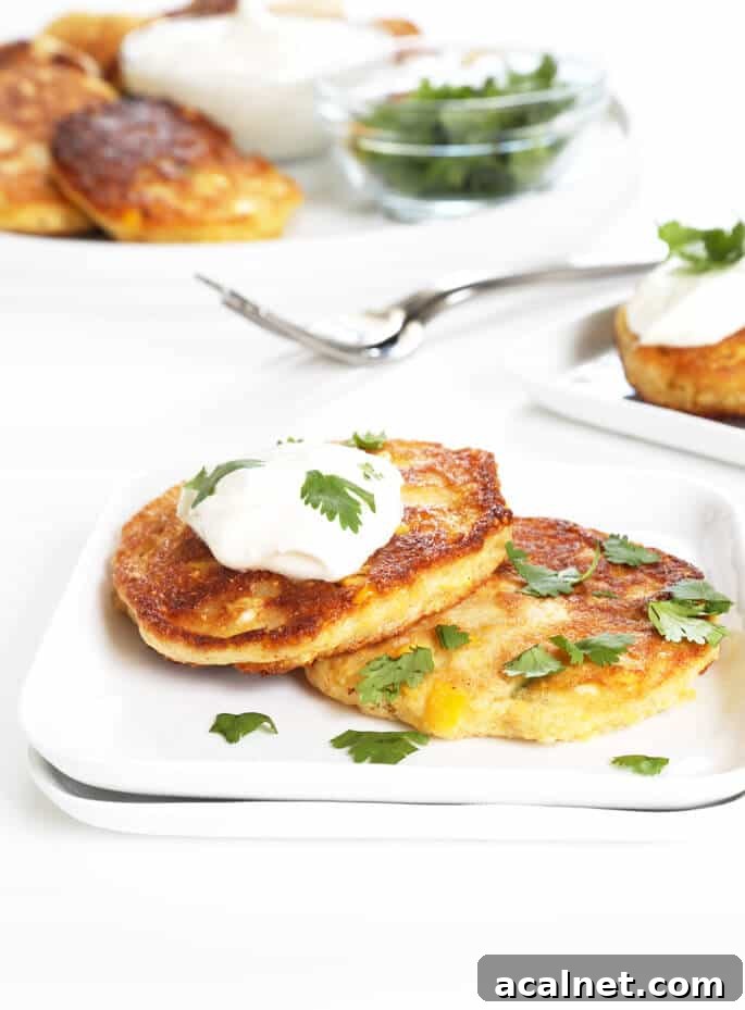 Savory Gluten-Free Corn Cakes Recipe for Crispy, Flavorful Bites 5 2 corn cakes on a white plate with sour cream and herbs on top