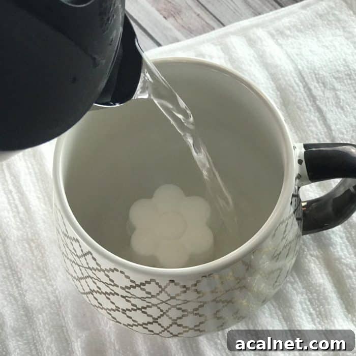 pouring hot water into mug with flower shaped tea tree essential oil facial steamer tab to activate steamer