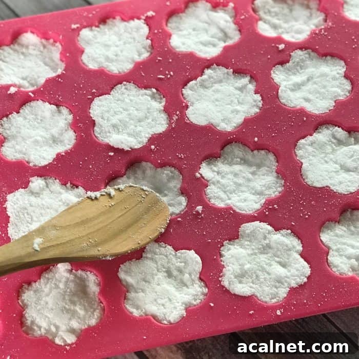 pressing mixture for tea tree essential oil facial steamer tabs into flower shaped silicone molds with wooden spoon
