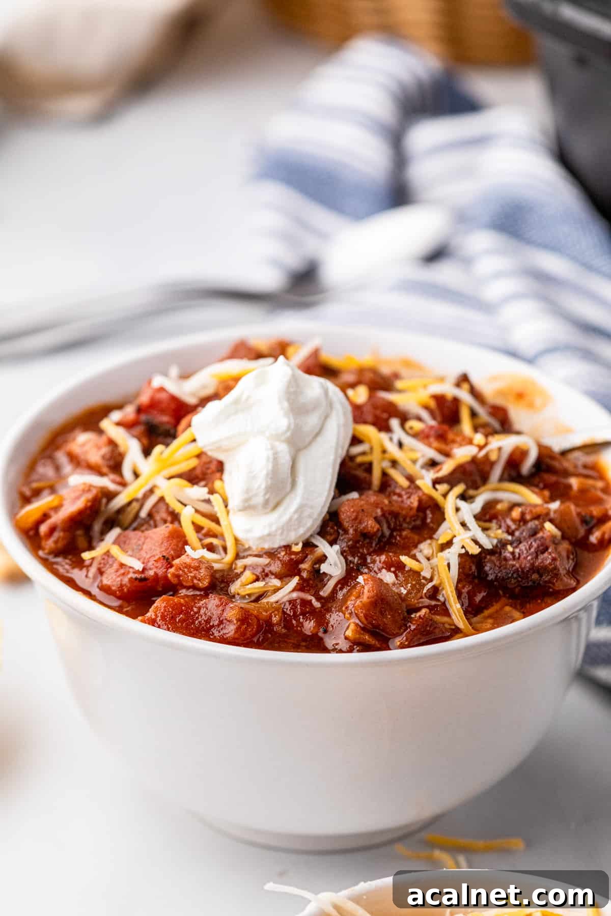 Smoked Brisket Chili in bowl with sour cream and shredded cheese toppings