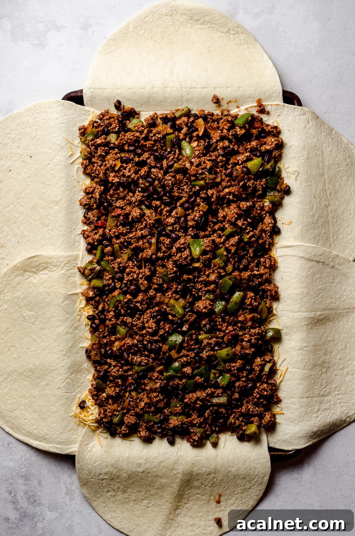Sheet Pan Quesadillas: Quick Oven-Baked Mexican Dinner 11 Adding ground beef to a sheet pan filled with tortillas.