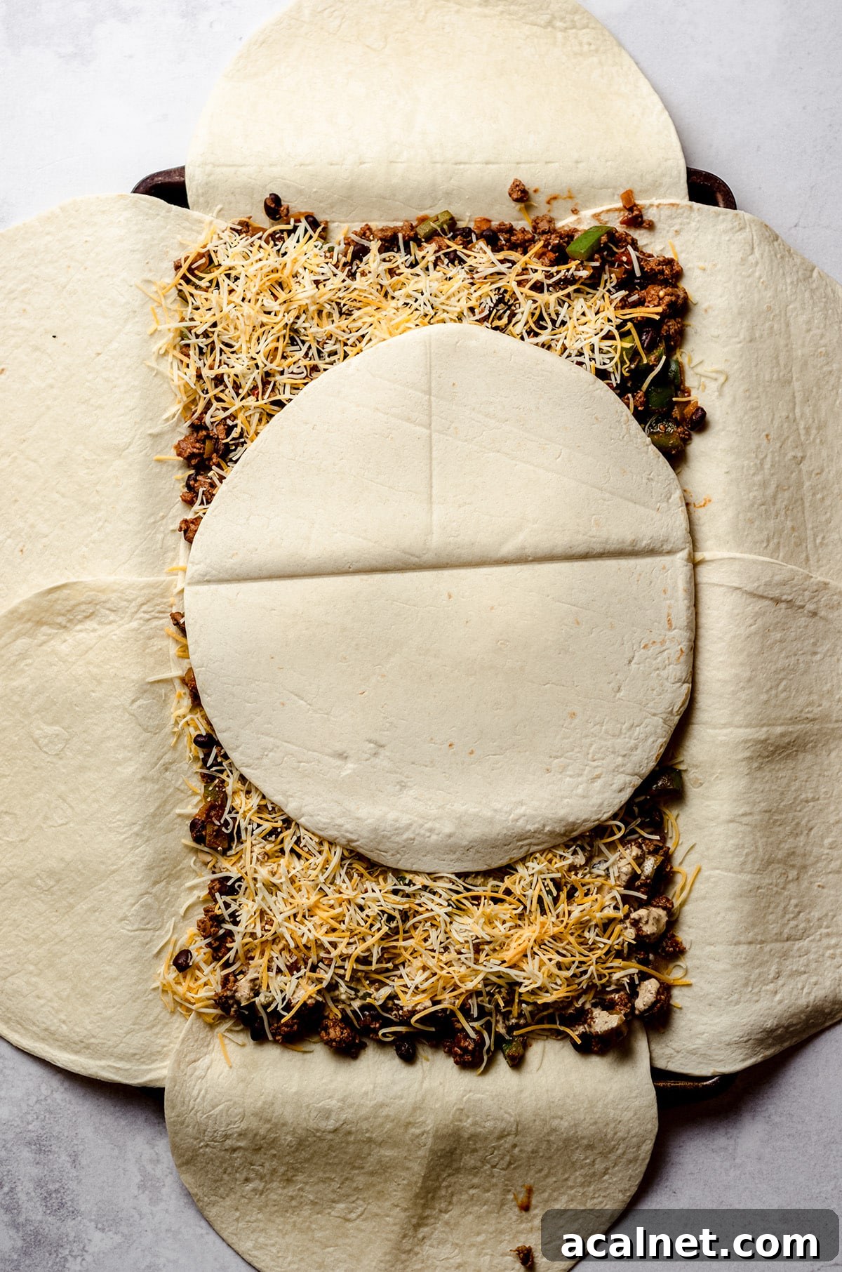 Sheet Pan Quesadillas: Quick Oven-Baked Mexican Dinner 13 Adding a tortilla on top of a giant sheet pan quesadilla.
