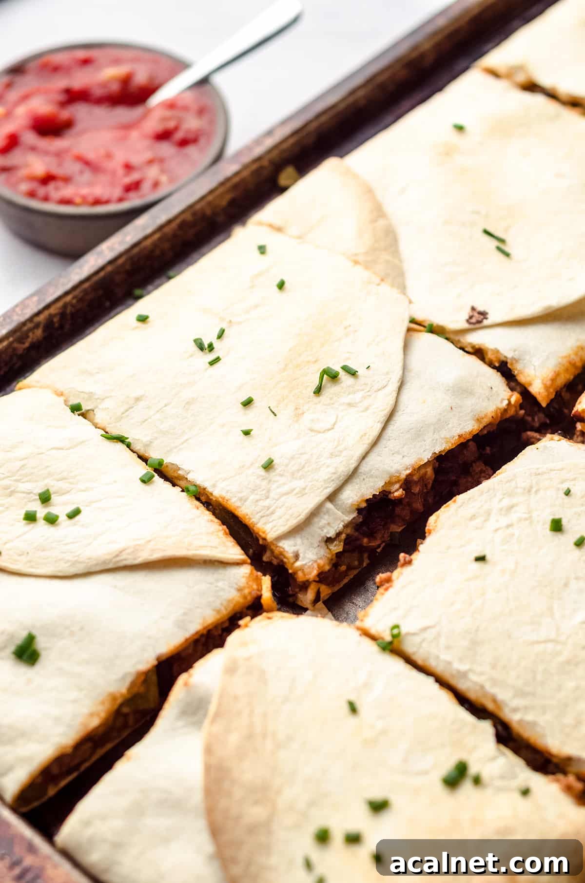 Sheet Pan Quesadillas: Quick Oven-Baked Mexican Dinner 17 A sheet pan filled with square flour tortilla wrapped quesadillas.