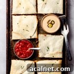 Sheet Pan Quesadillas: Quick Oven-Baked Mexican Dinner 19 An overhead shot of a sheet pan filled with square quesadillas and served with bowls of sauce and salsa.