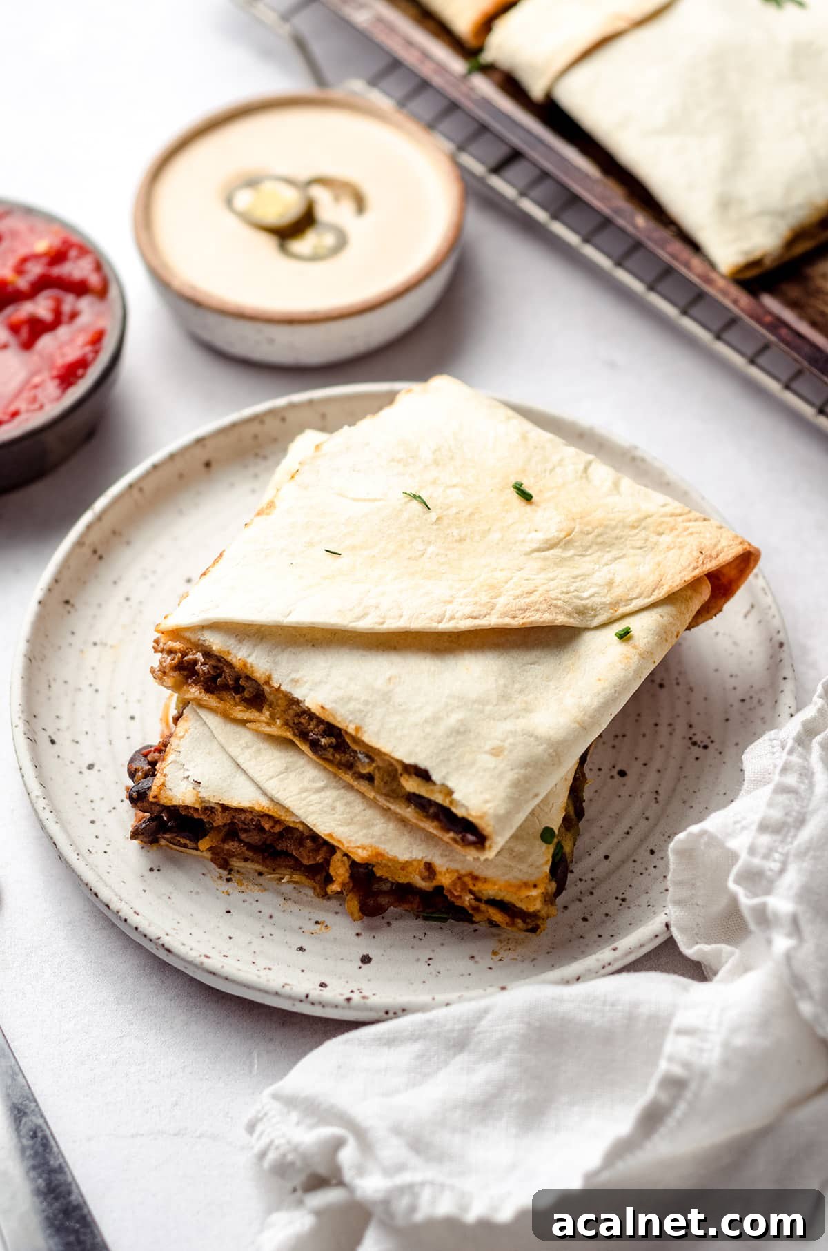 Sheet Pan Quesadillas: Quick Oven-Baked Mexican Dinner 8 Two square tortilla wraps on a plate.