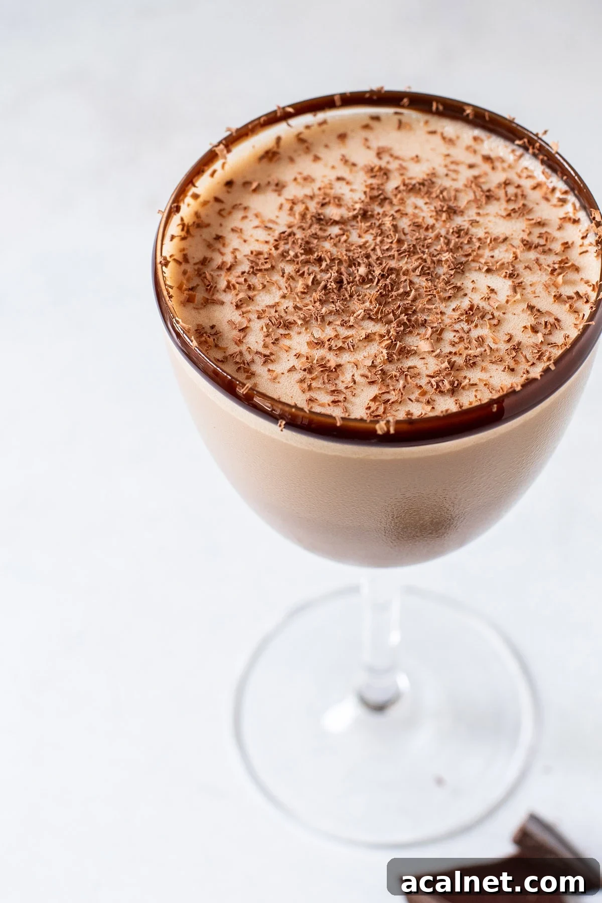 A rich chocolate martini served in a Nick and Nora glass with a chocolate rim and dusting of grated chocolate shavings.