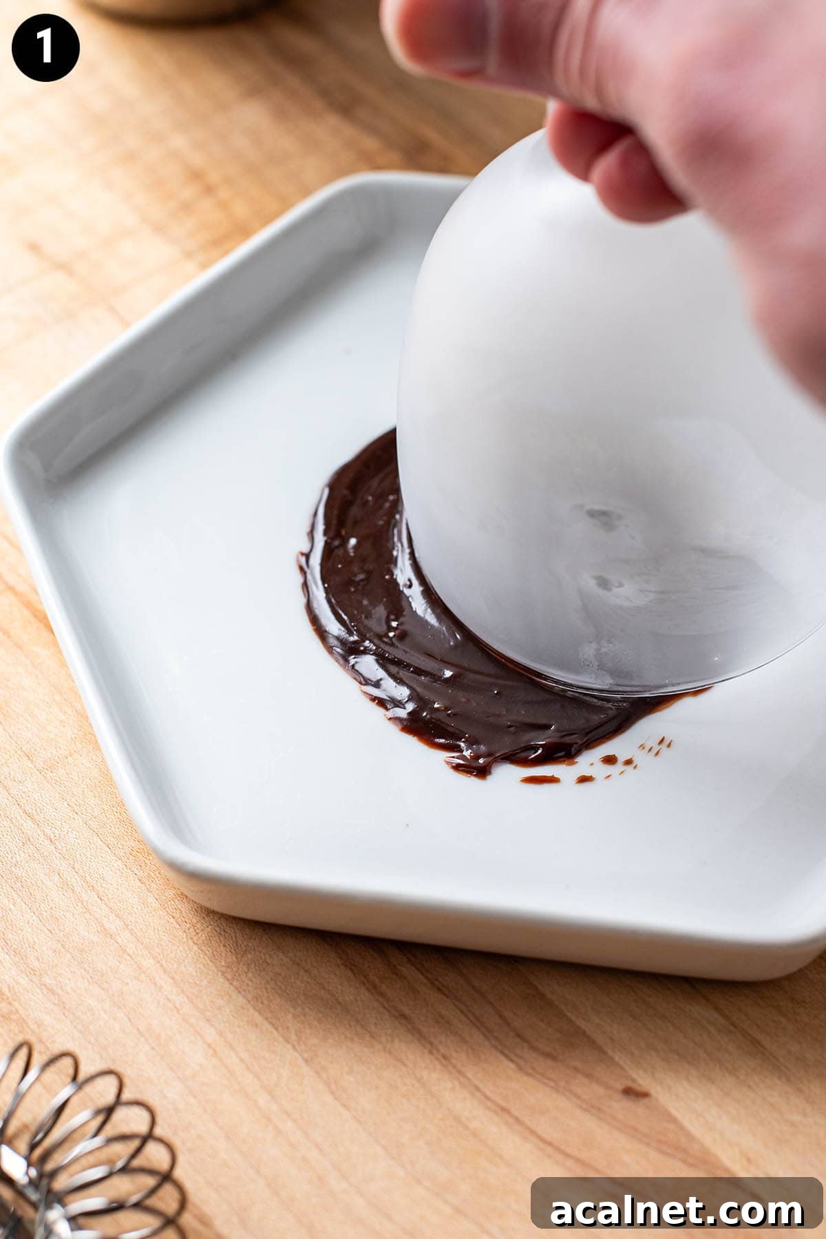 Adding a rim of chocolate to a frozen Nick and Nora glass by dipping it in melted chocolate.