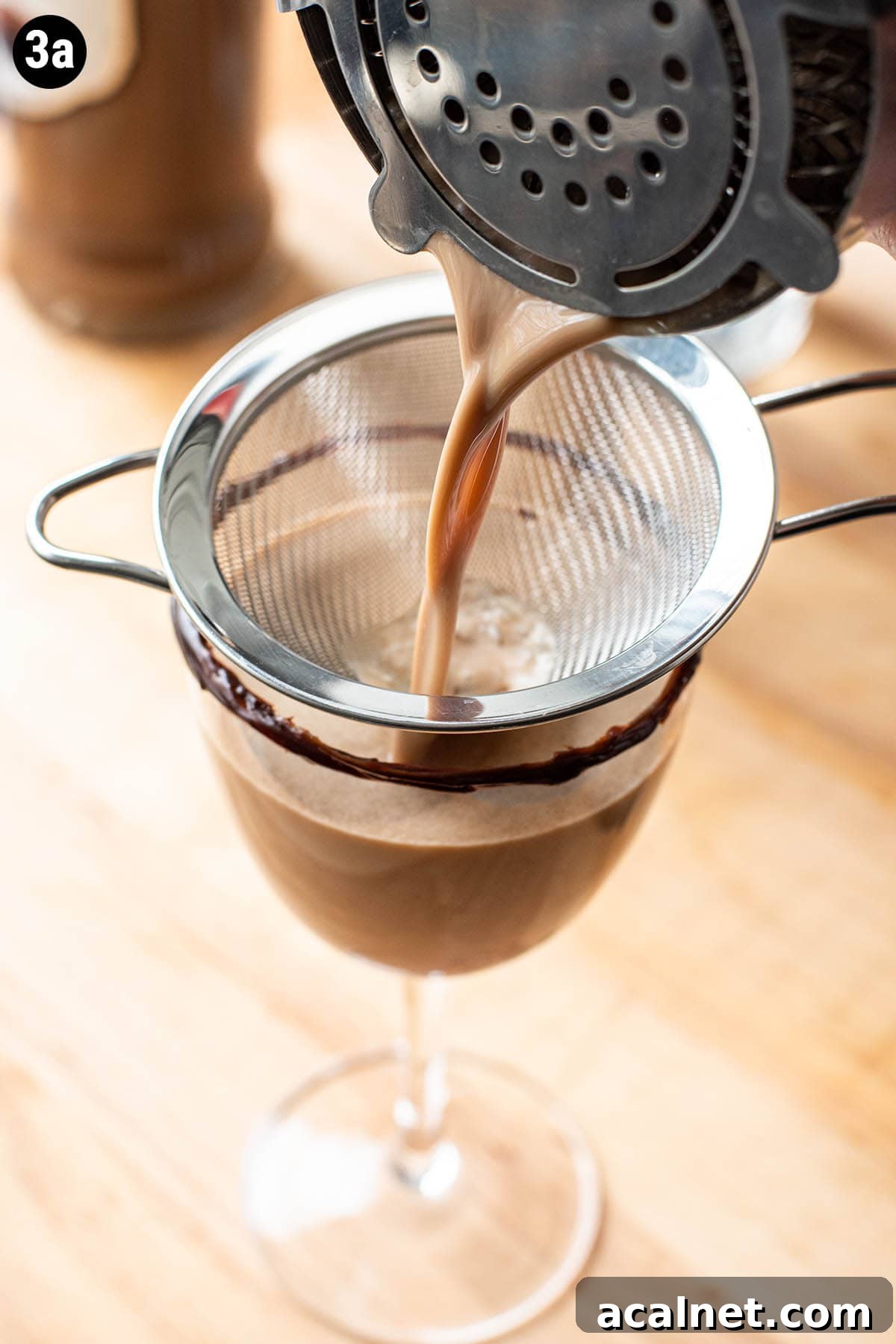 Double straining a chocolate martini into a coupe glass.