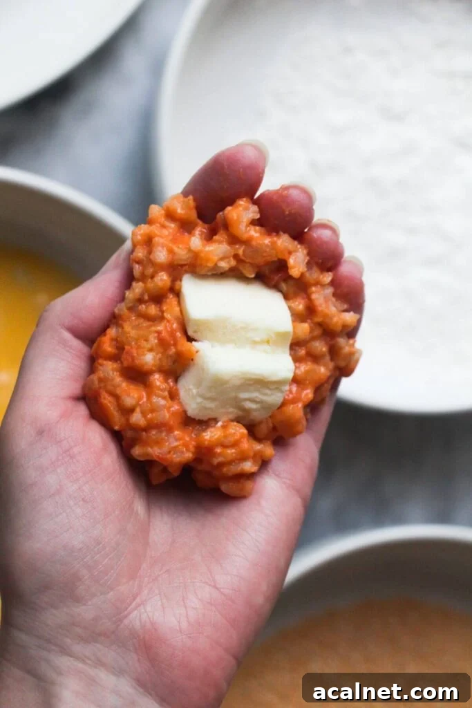 Gochujang Cheesy Risotto with Creamy Korean Chili Flavor 12 Mozzarella pieces in risotto in a hand, about to be formed into arancini.