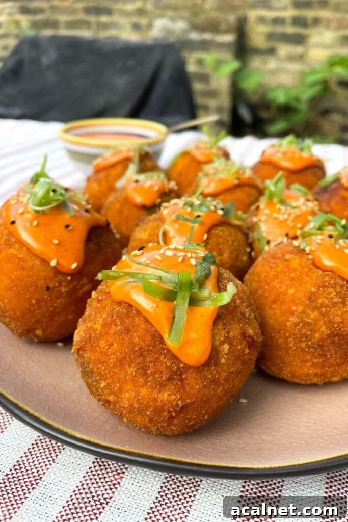 Gochujang Cheesy Risotto with Creamy Korean Chili Flavor 15 Crispy arancini balls on a pink plate and topped with spicy aioli on top.