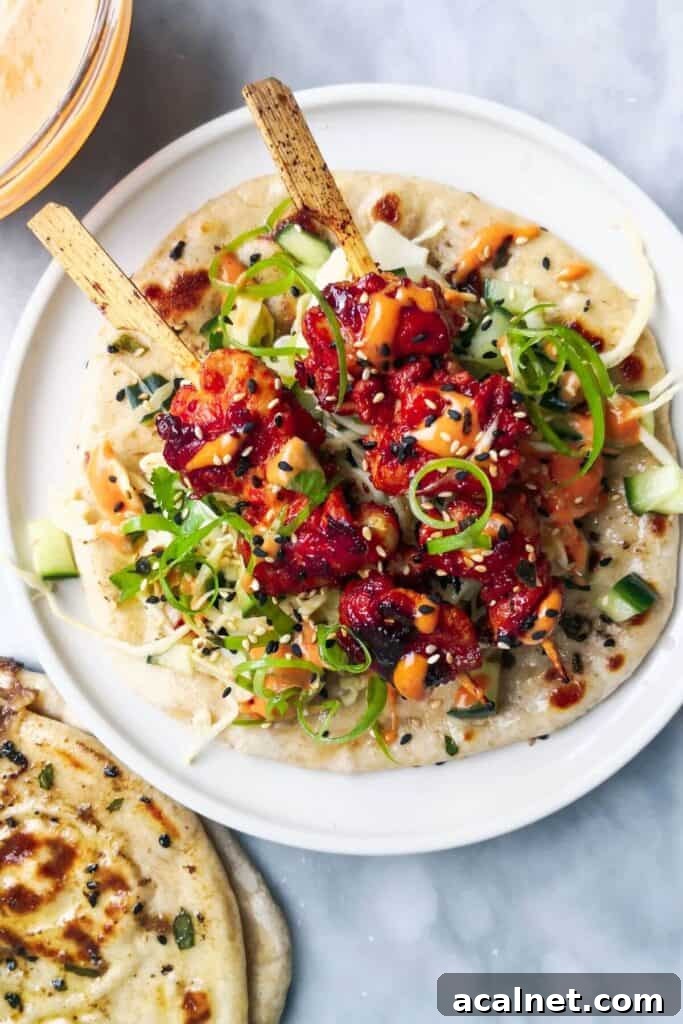 Gochujang Cheesy Risotto with Creamy Korean Chili Flavor 16 2 gochujang chicken skewers on top of slaw, on a flatbread on a white plate, with flatbreads and gochujang aioli on the side.