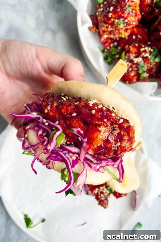 Gochujang Cheesy Risotto with Creamy Korean Chili Flavor 18 Hand holding up a bao bun filled with Korean fried chicken and red cabbage slaw.