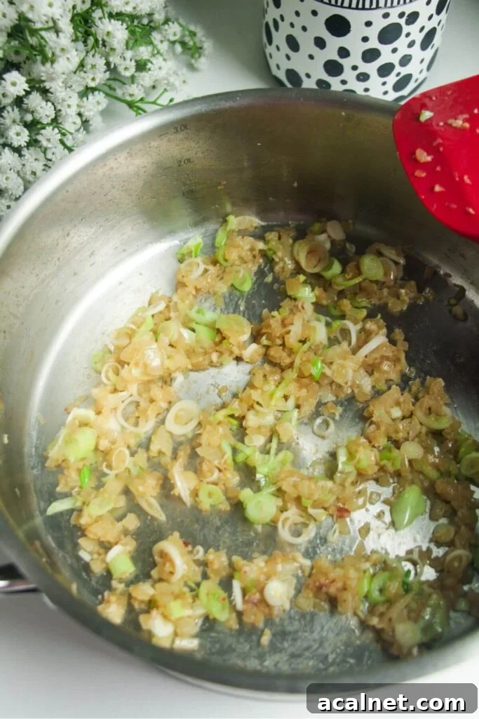 Gochujang Cheesy Risotto with Creamy Korean Chili Flavor 5 Onion, garlic and ginger cooking in a large pan.