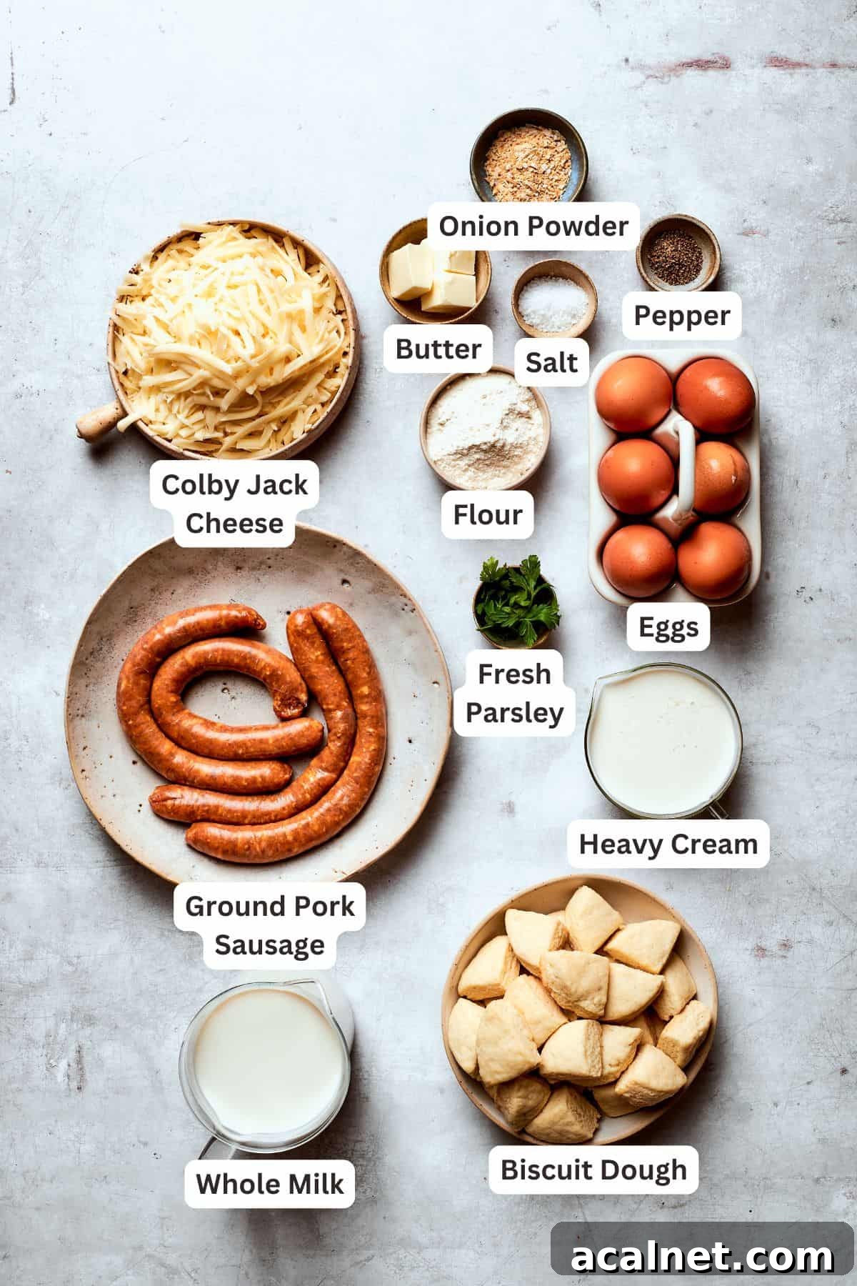Biscuits and gravy casserole stars flaky biscuits, a rich and creamy sauce, and hearty sausage! Great for brunch or dinner! Ingredients for biscuits and gravy casserole are text-labeled.