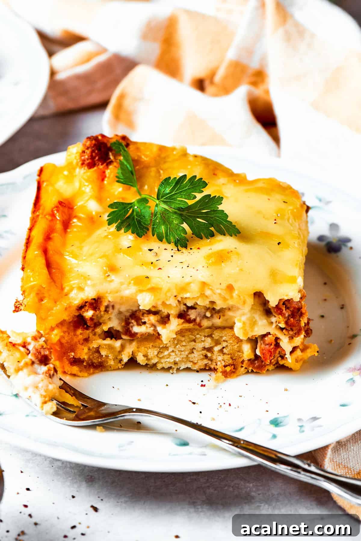 Biscuits and gravy casserole stars flaky biscuits, a rich and creamy sauce, and hearty sausage! Great for brunch or dinner! A slice of biscuits and gravy casserole served on a dinner plate.