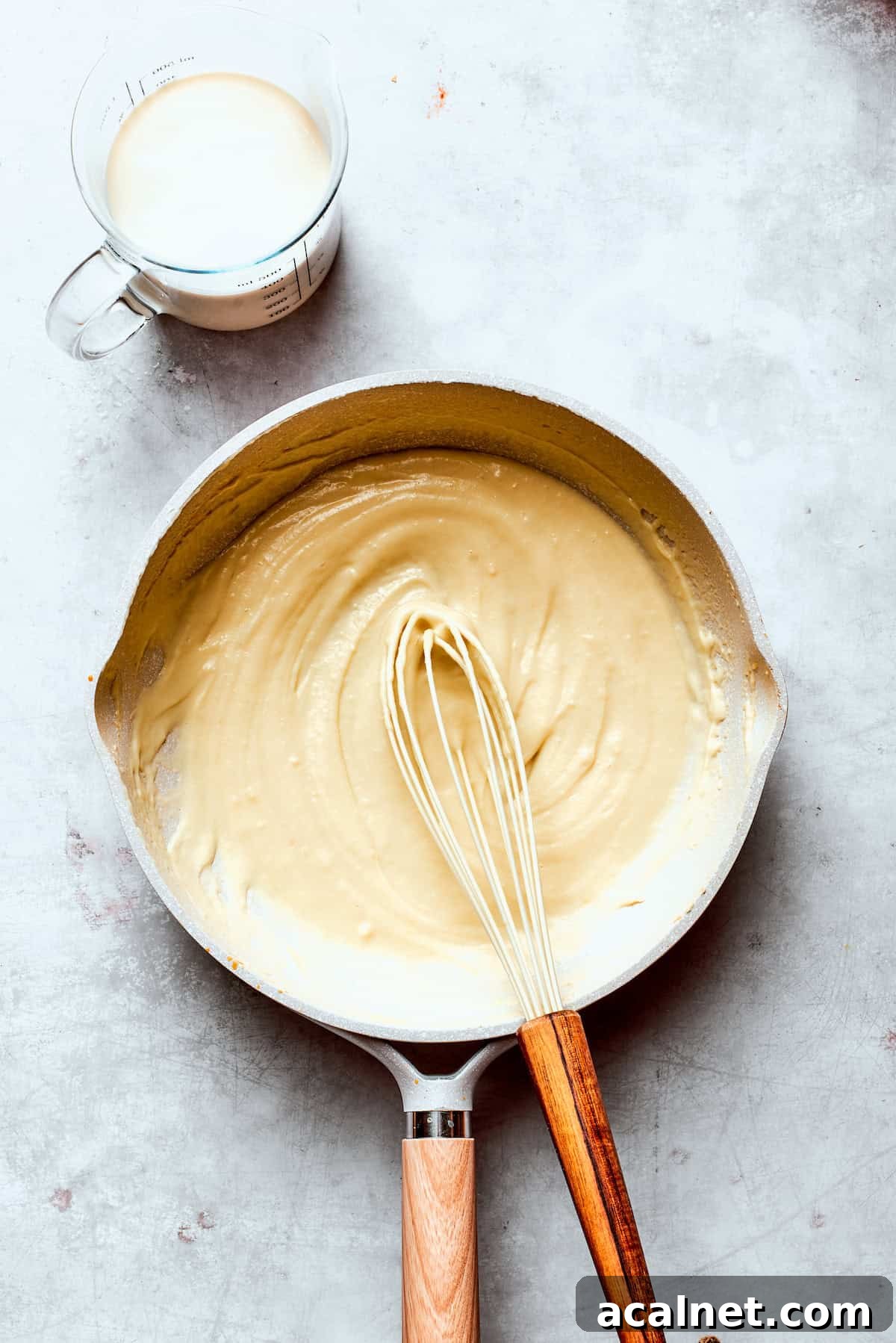 Whisk in milk Milk is whisked into a skillet of roux.