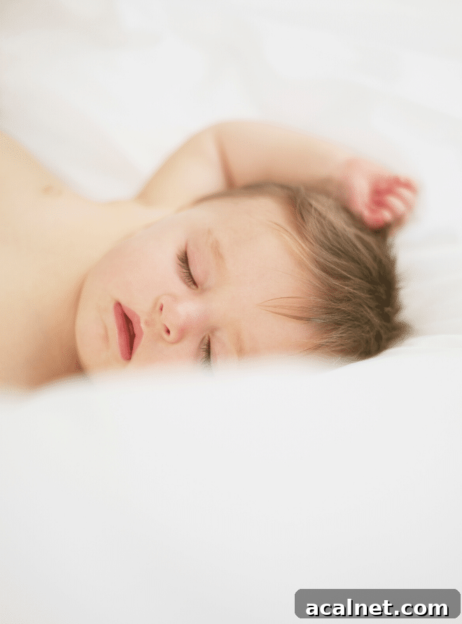 baby boy asleep on white sheets with his arm over his head - baby sleep