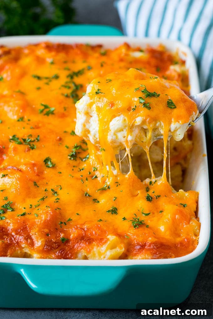 A spoon serving up a portion of cheesy potatoes topped with chopped parsley.