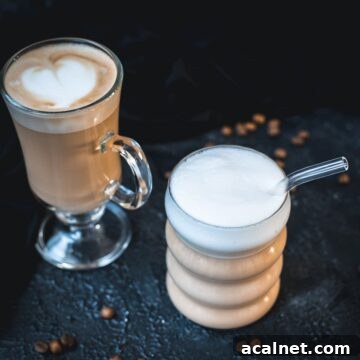 2 glasses filled with delicious vanilla latte. placed on dark ground. Left on has a latte art heart on top.