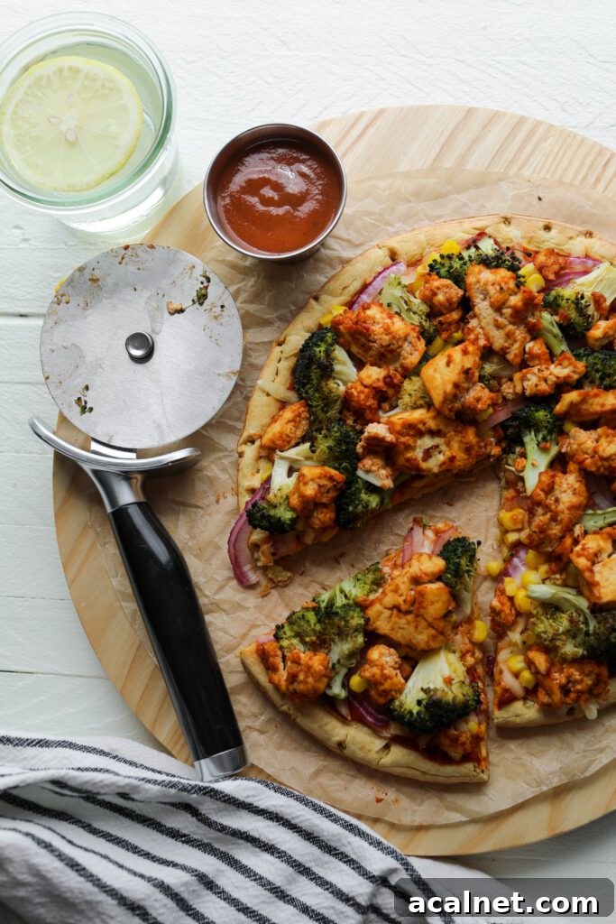 BBQ Tofu Pizza with slice missing and pizza cutter on wooden board by Flora & Vino