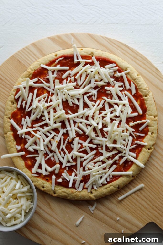 Chickpea crust with BBQ sauce and shredded vegan cheese on wooden board by Flora & Vino