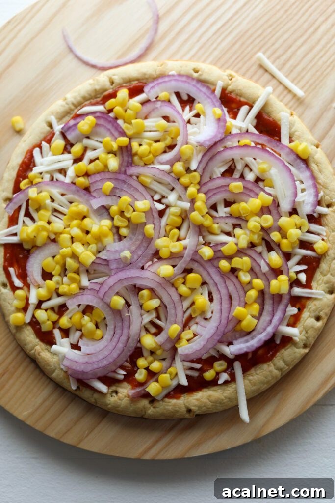 chickpea crust topped with BBQ sauce, vegan shredded cheese, cooked corn, and red onion by Flora & Vino 
