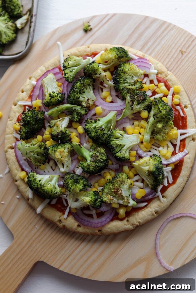 chickpea crust topped with BBQ sauce, vegan shredded cheese, red onion, cooked corn, and roasted broccoli by Flora & Vino