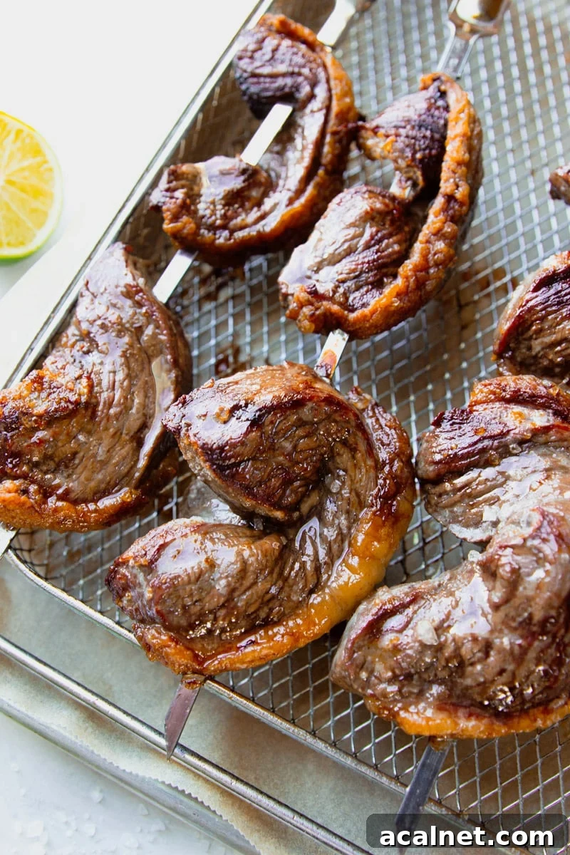 Air Fryer Picanha Steak Recipe: Perfect Crispy Crust & Juicy Center 2 Piranha steak on a skewer with a lime.
