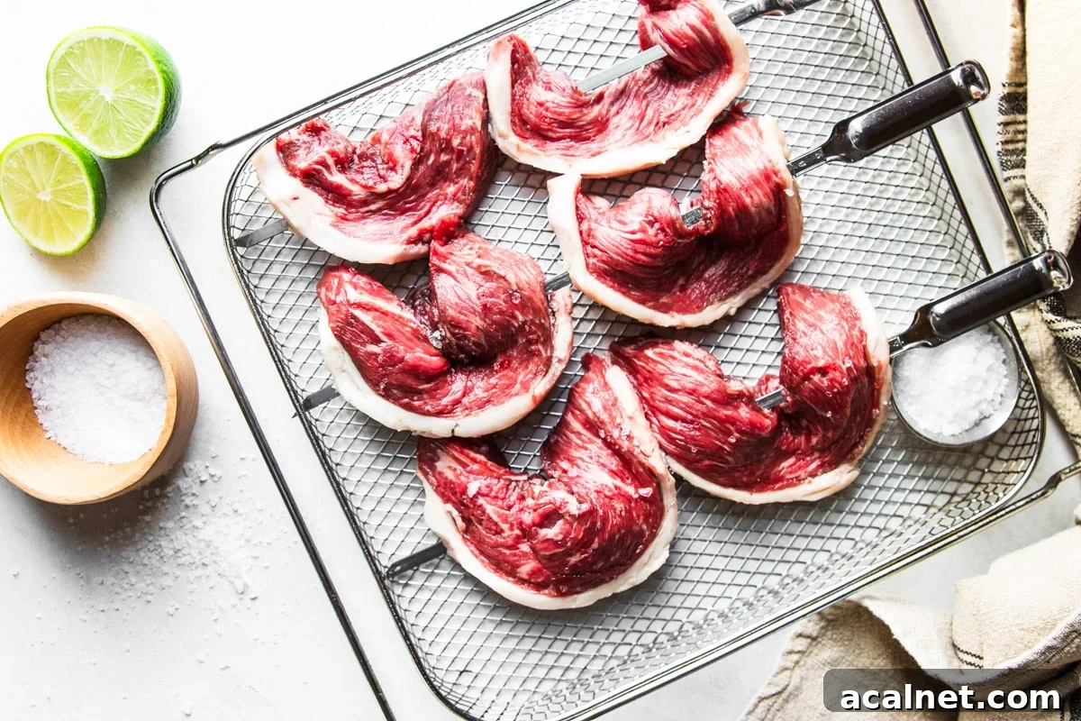 Air Fryer Picanha Steak Recipe: Perfect Crispy Crust & Juicy Center 11 Picanha steak on skewers with salt and limes with a white and black dish towel.
