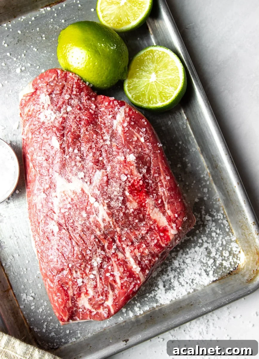 Air Fryer Picanha Steak Recipe: Perfect Crispy Crust & Juicy Center 9 Raw picanha steak seasoned with salt and limes on a stainless steel baking sheet.