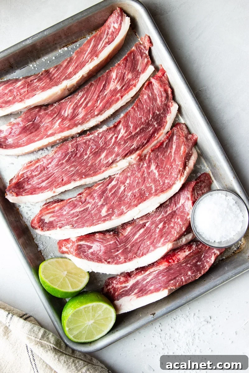 Air Fryer Picanha Steak Recipe: Perfect Crispy Crust & Juicy Center 10 Piranha steak slices with salt and limes on a baking sheet.
