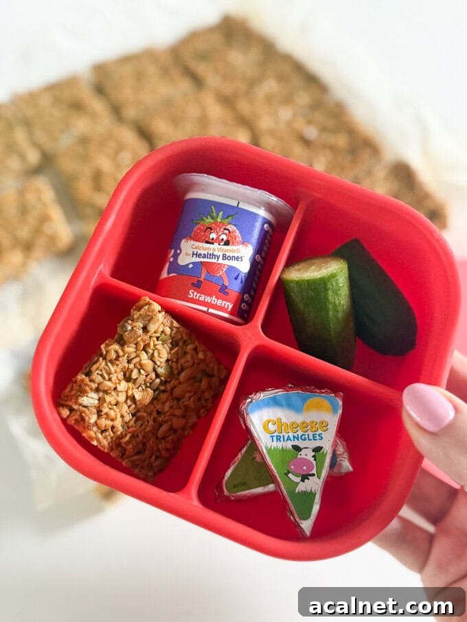Nut-Free Oat Flapjacks Recipe — Gluten-Friendly Snack 3 One slice of nut free flapjack served in a four section bright red snack box along side a small yogurt, cucumber and cheese triangles.