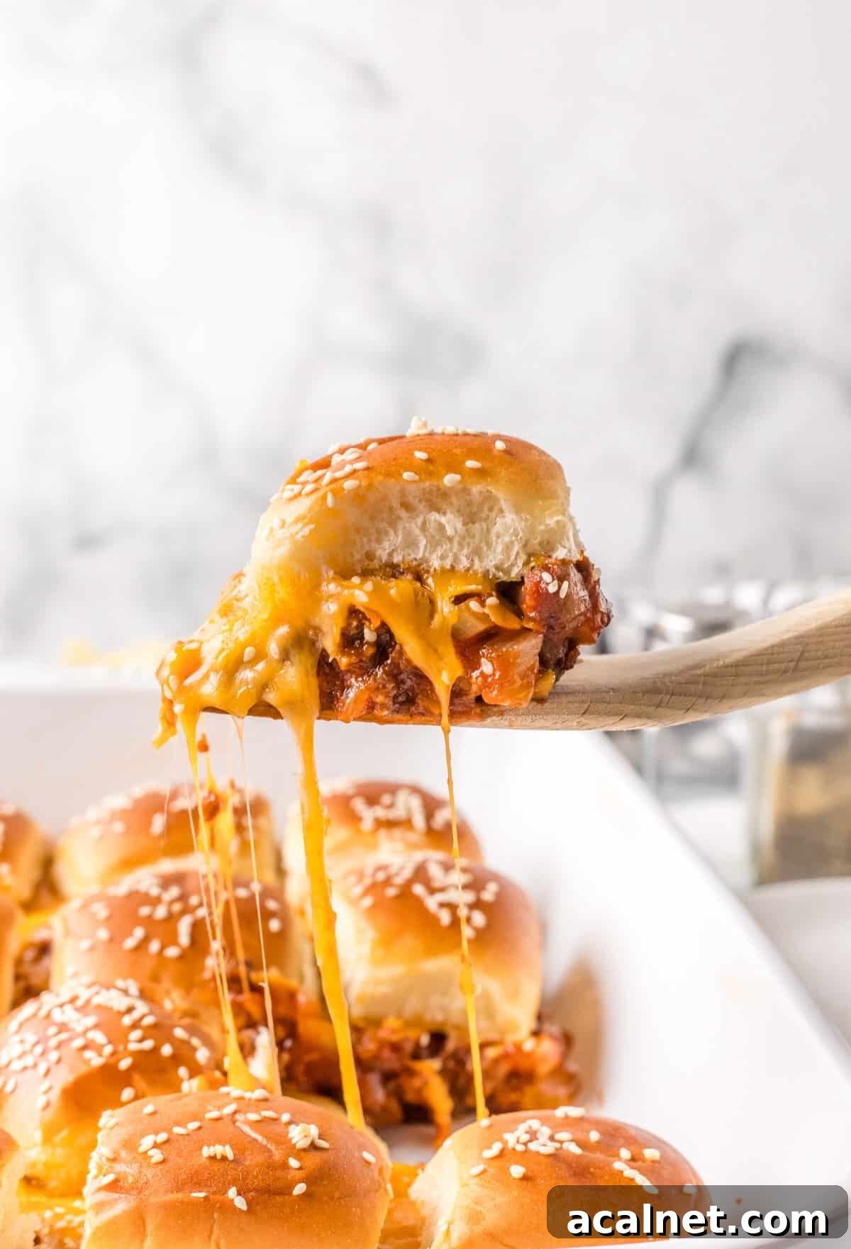 A cheesy sloppy joe slider being served.
